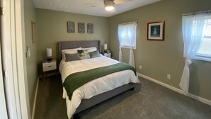 A bedroom with a bed, a ceiling fan, a nightstand, and a window with curtains. - Cozy cottage for a couple's weekend get away! (Russells Point)