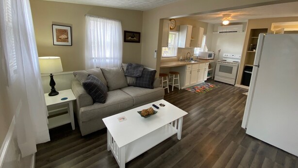 A compact living space with a kitchenette, a sofa, a coffee table, and a dining area. - Cozy cottage for a couple's weekend get away! (Russells Point)