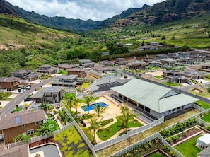 Residential community with single-family homes and townhouses, surrounded by lush greenery and a scenic mountain backdrop.