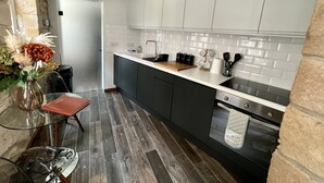 A modern kitchen with dark cabinets, a white countertop, and a tiled backsplash. - Luxurious Bolthole (Matlock)
