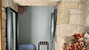 A bedroom with a bed, a chair, a stone wall, and a vase with flowers. - Luxurious Bolthole (Matlock)