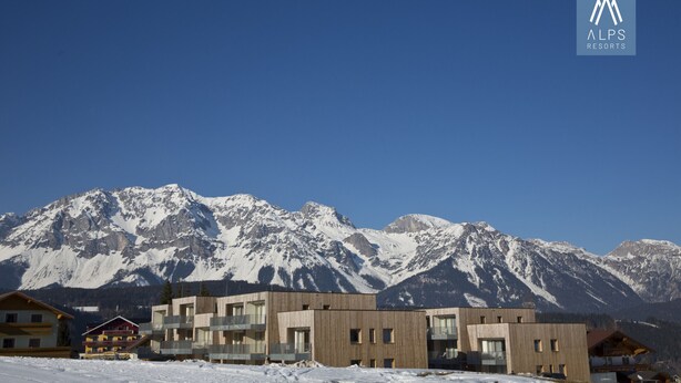 A modern building with multiple balconies and a mountain backdrop.
