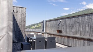 An outdoor patio with a wooden fence, a table with chairs, and a view of a green landscape in the background.