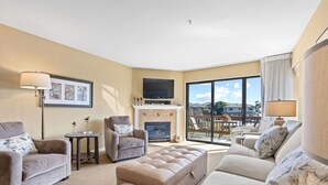 A living room with a fireplace, a television, and a balcony with a view of the city. - Closely located to Seascape Golf Course & Seascape Village (Aptos)