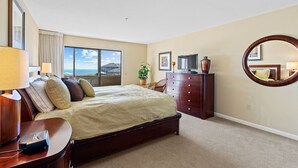 A hotel room with a large bed, a dresser, a mirror, and a window with a view of the sky and buildings. - Closely located to Seascape Golf Course & Seascape Village (Aptos)