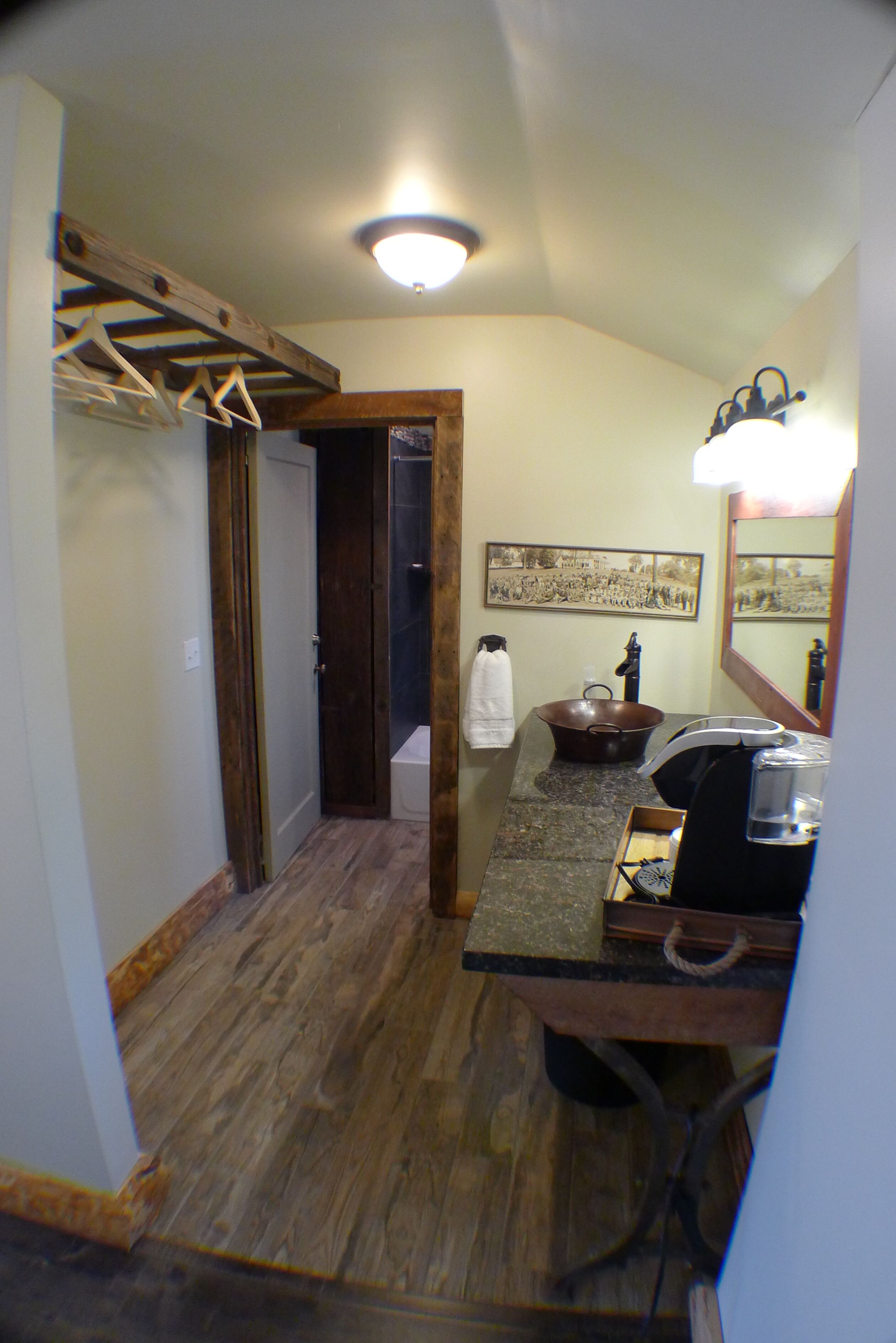 A bathroom with a wooden floor, a sink, a mirror, and a towel rack.