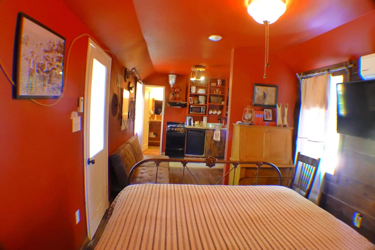 A room with a bed, a kitchenette, and a dining area.