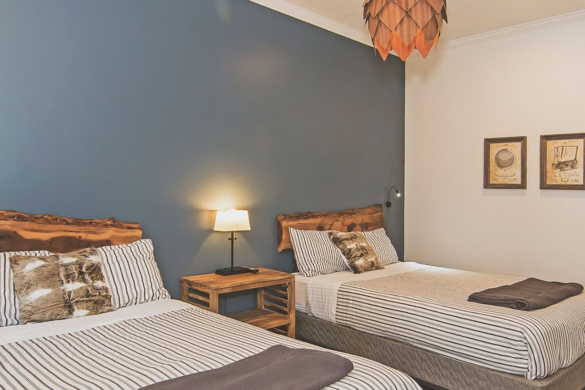 A hotel room with two beds, a nightstand, a lamp, and a ceiling light fixture.