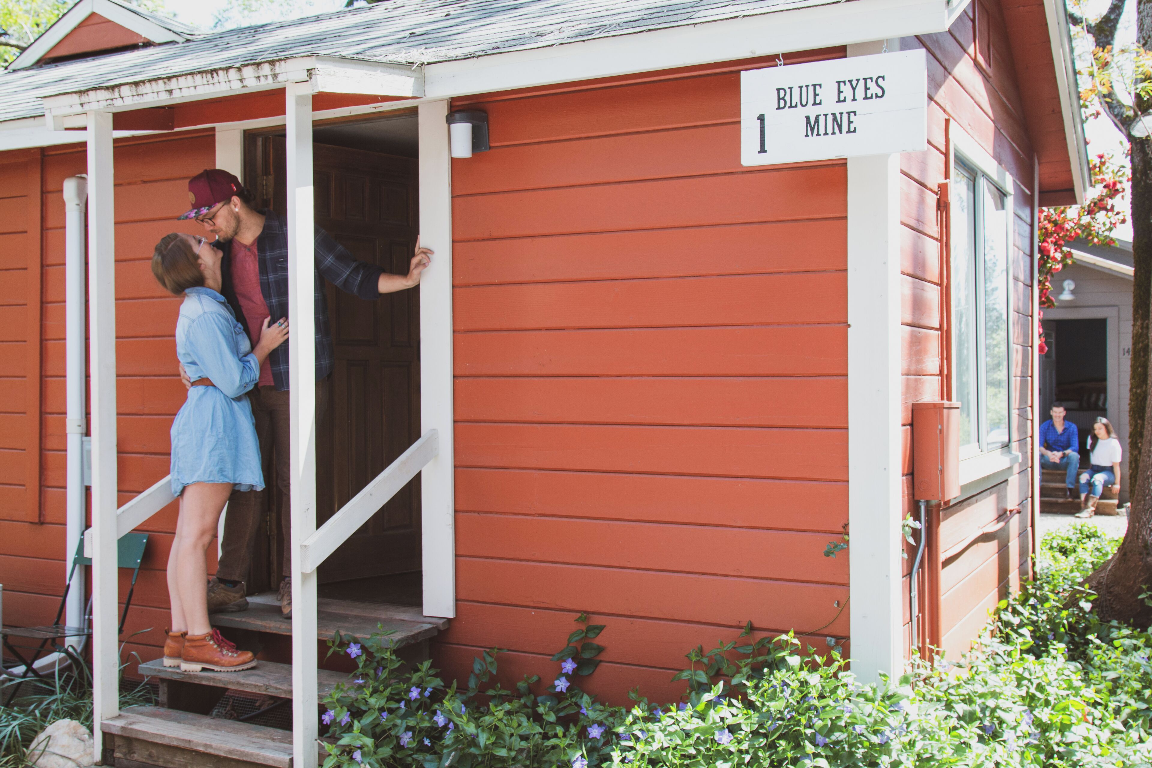 A small red building with a porch and a sign that reads "Blue Eyes Mine".