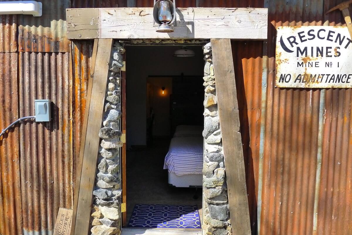 A rustic entrance with a wooden archway, a lantern, and a sign stating "Crescent Mines Mine No 1 No Admission."