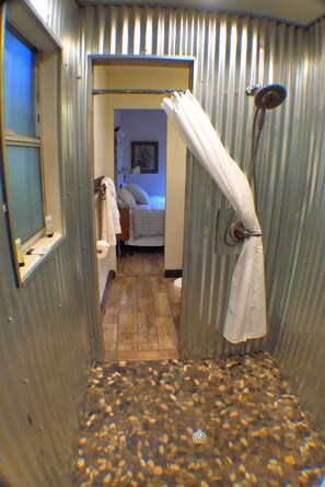A bathroom with a shower curtain, a towel rack, and a wooden floor. - Miners Camp (Foresthill)