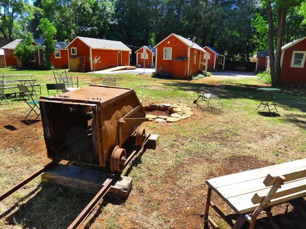 Un camping con varias cabañas rojas, una parrilla portátil y mesas de picnic.
