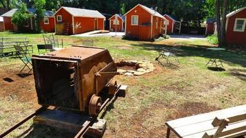 Un camping con varias cabañas rojas, una parrilla portátil y mesas de picnic.
