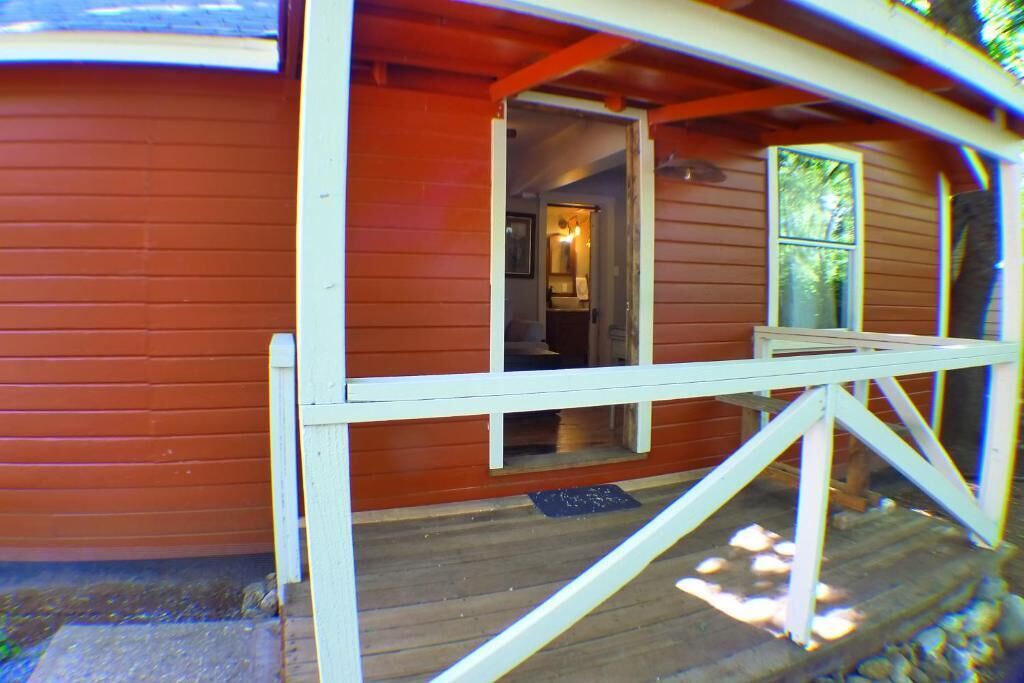 Una baita di legno con un portico e un'apertura che dà su un ambiente interno.