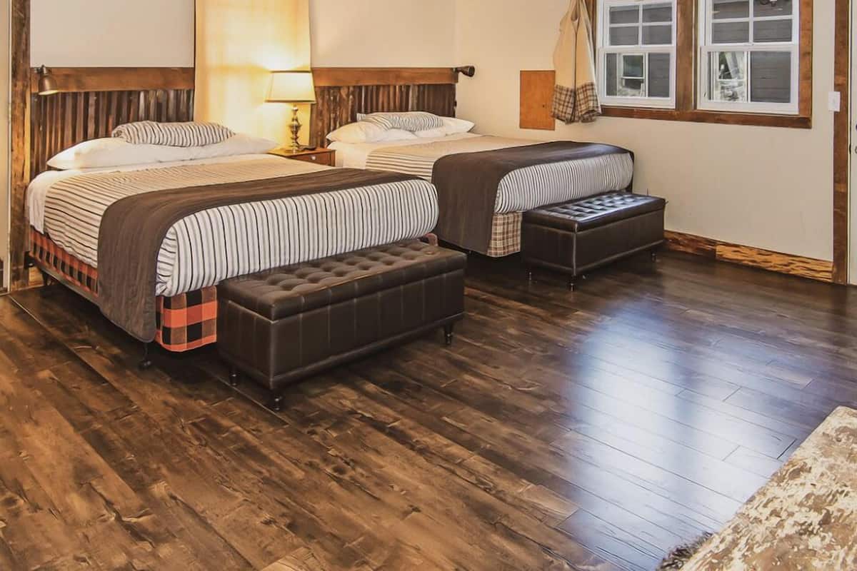 A bedroom with two beds, a ceiling fan, and a window with curtains.