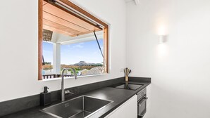 A modern kitchen with a large window, a built-in sink, and a stove.