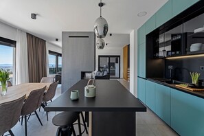 A modern kitchen with a central island, dark cabinetry, and a view to the living area. - Villa Fortress, private pool, Game room, sea views (Klis)