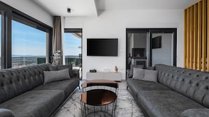 Una sala de estar moderna con dos sofás grises, una mesa de centro y un televisor de pantalla plana montado en la pared.