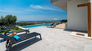 Zona de piscina en la azotea con sillones reclinables y vistas a la ciudad.