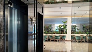 A modern lobby with a marble floor, a reception desk, and a seating area with green chairs. - PREMIUM SUNRISE (Golem)