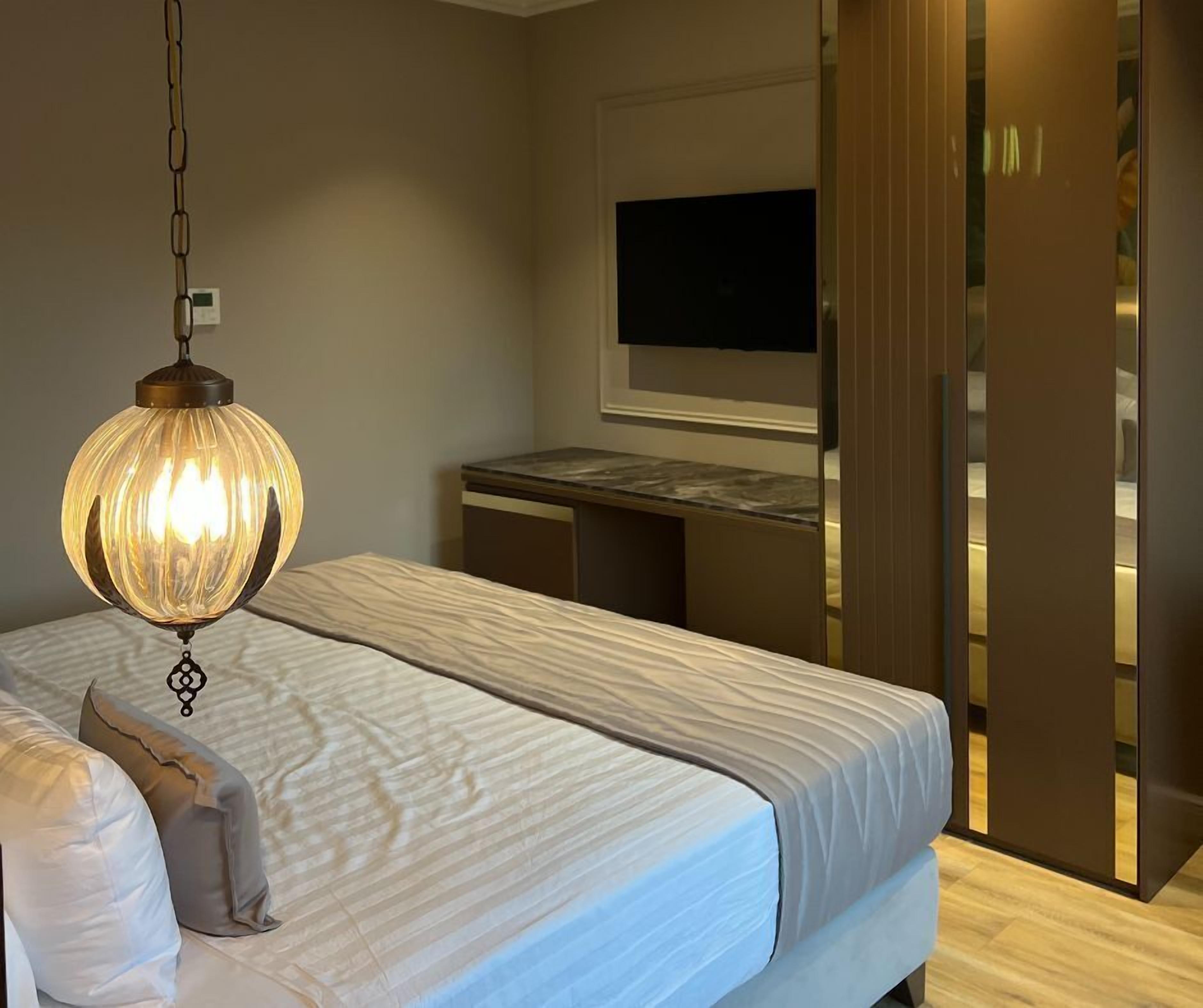 Quarto com cama, escrivaninha, televisão e porta.