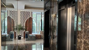 A modern lobby with a polished marble floor, a reception desk, seating area with patterned sofas, decorative wall panels, and a large mirror reflecting the space. - PREMIUM SUNRISE (Golem)