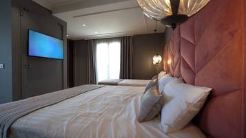 Habitación de hotel con dos camas, un televisor de pantalla plana, un ventanal con cortinas y una lámpara decorativa en la pared.