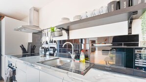 A modern kitchen with a built-in dishwasher, stainless steel appliances, and a marble countertop.
