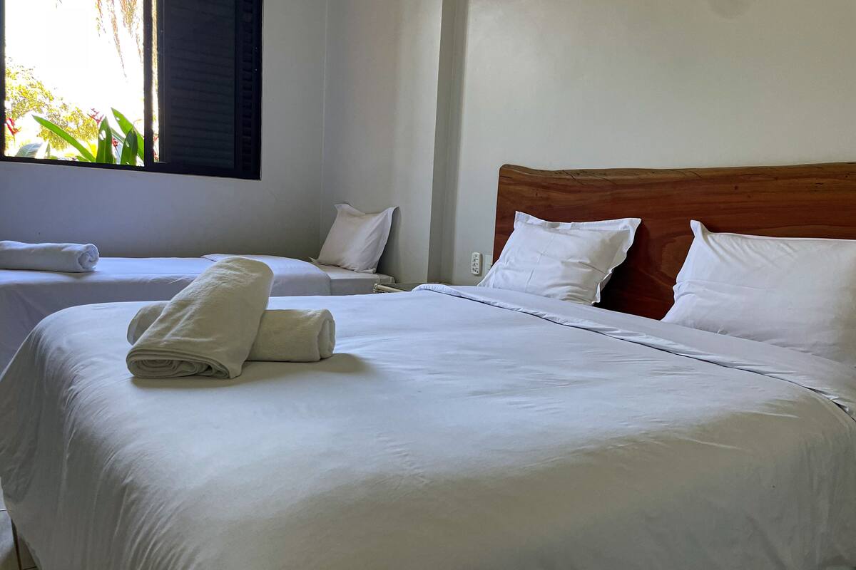 Ein Hotelzimmer mit zwei Betten, jeweils mit weißer Bettwäsche und Kissen, und einem hölzernen Kopfteil.