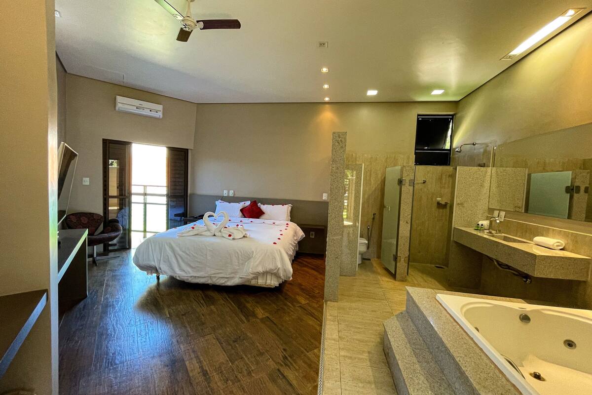 Ein modernes Hotelzimmer mit einem großen Bett, einer Duschkabine und einem Badezimmer mit einer Badewanne.