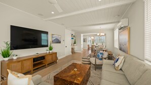 A modern living room with a large flat-screen TV, wooden entertainment unit, and a coffee table. - Eco Smart Home, Canalfront with Pool! (Cortez)