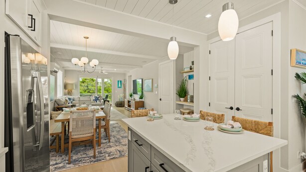 A spacious kitchen with a large island, modern appliances, and a dining area with a chandelier. - Eco Smart Home, Canalfront with Pool! (Cortez)
