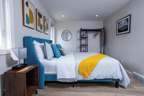 A bedroom with a bed, bedside table, lamp, and artwork on the walls. - Modern Living next to Titletown, Green Getaway! (Green Bay)