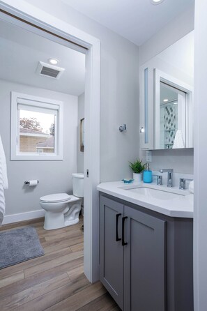 A modern bathroom with a toilet, sink, mirror, and window. - Modern Living next to Titletown, Green Getaway! (Green Bay)