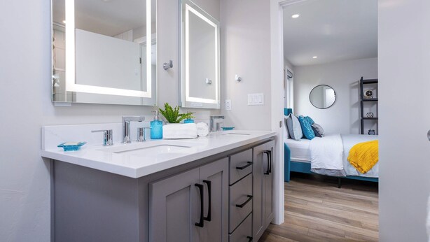 Un baño moderno con un espejo grande, lavamanos dobles y una planta en maceta.