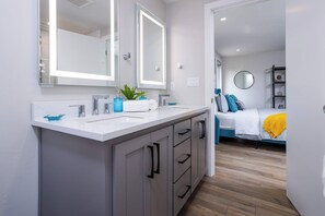 A modern bathroom with a large mirror, dual sinks, and a potted plant. - Modern Home in Green Bay Across from Lambeau Field - Titletown District Sleeps 8 (Green Bay)