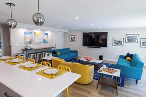 A modern living room with a dining area, blue sofas, yellow chairs, and a flat-screen TV on the wall. - Modern Living next to Titletown, Green Getaway! (Green Bay)