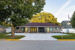 A two-story building with a dark roof, a front entrance, and a flagpole. - Modern Living next to Titletown, Green Getaway! (Green Bay)