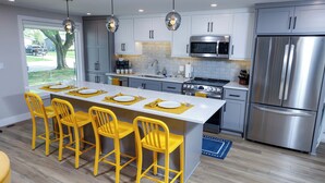 Una cocina moderna con una isla central, electrodomésticos de acero inoxidable y sillas amarillas.