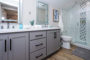 Une salle de bain moderne avec un grand miroir, une douche et des toilettes.