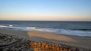 Een strand met een hek en duinen op de voorgrond.