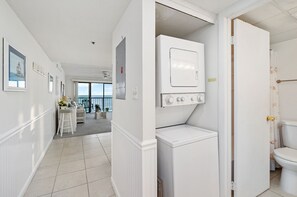 Enjoy a bright and airy space with a large window offering views of the outdoors, a bathroom with a toilet and sink, and a laundry area with a washing machine and dryer.