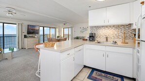 Een moderne keuken met witte kasten, een groot eiland en uitzicht op de oceaan.