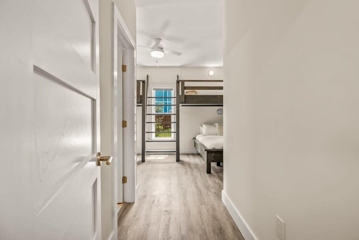 Un couloir étroit avec un lit superposé, un ventilateur de plafond et une fenêtre donnant sur un paysage verdoyant.