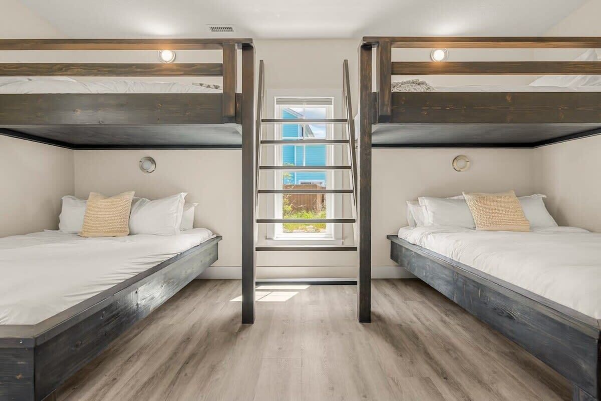 Ein Zimmer mit zwei Etagenbetten, einer zentralen Leiter und einem Fenster für natürliches Licht.