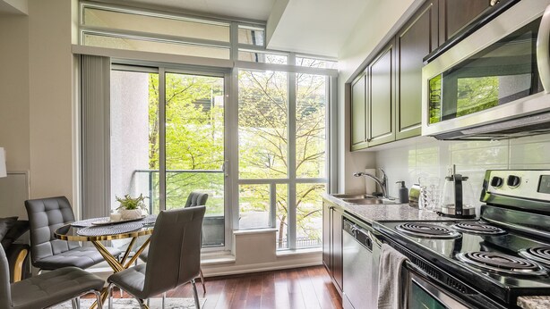 Una cocina moderna con un ventanal grande, una zona de comedor con una mesa redonda y sillas, y una estufa empotrada.