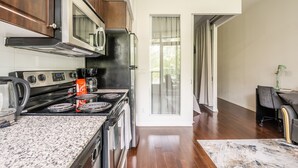 Una cocina moderna con estufa, microondas y horno. Hay una zona de comedor con mesa y sillas.