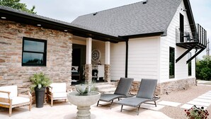 A stone and white house with a covered patio, outdoor seating, and a decorative fountain. - Sycamore Hill Guesthouse (Oklahoma County)
