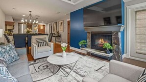 A modern living room with a fireplace, a dining area, and a kitchen. - NEW!The Louvre by SSR Top Luxury|1000SQF|2BR&2BTH ( BL# RES-11739 ) (Canmore)