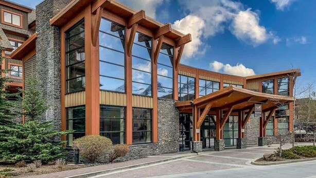 A modern building with large windows and a stone facade. - NEW!The Louvre by SSR Top Luxury|1000SQF|2BR&2BTH ( BL# RES-11739 ) (Canmore)
